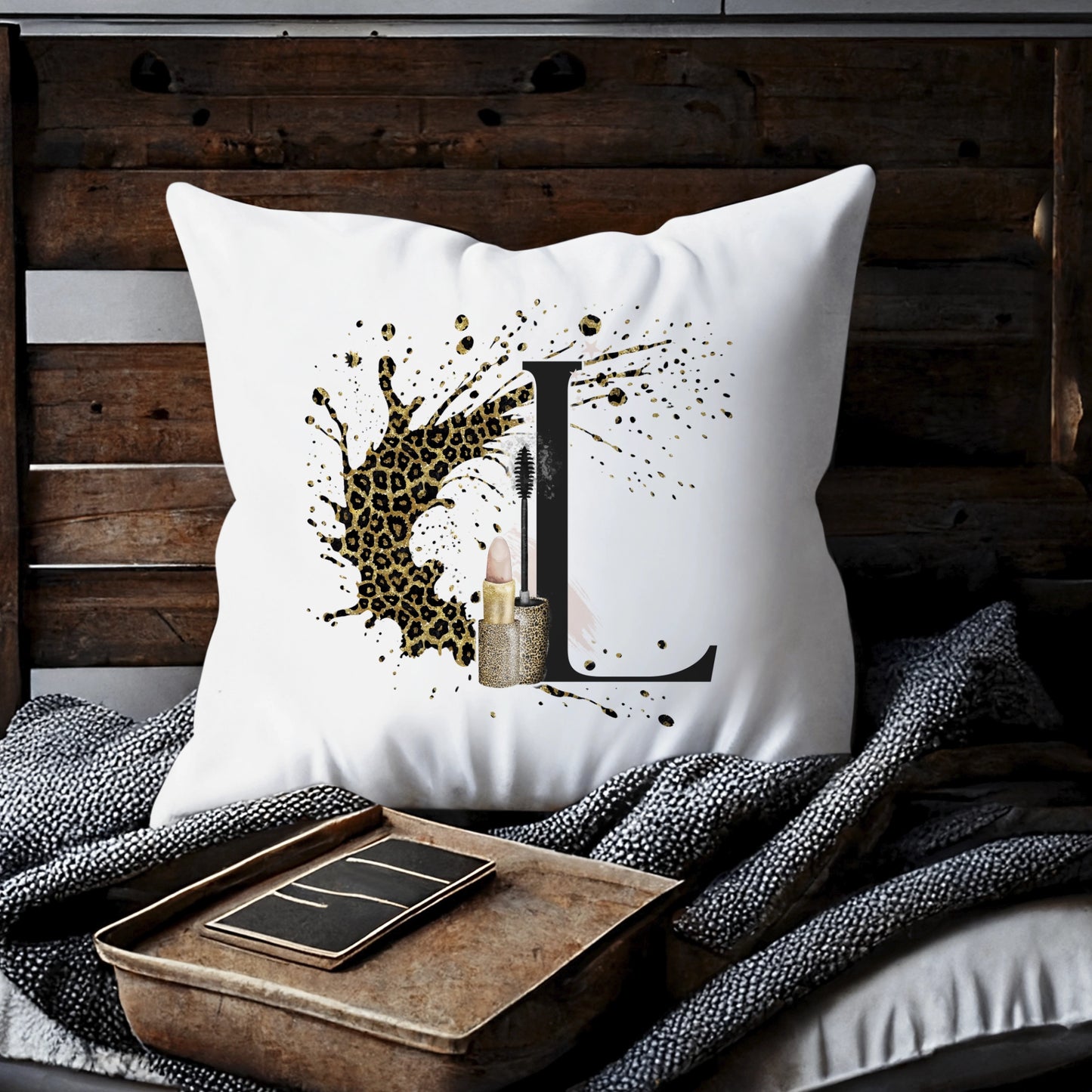 Cushion with a leopard print background splash and an initial letter L with a lipstick and mascara