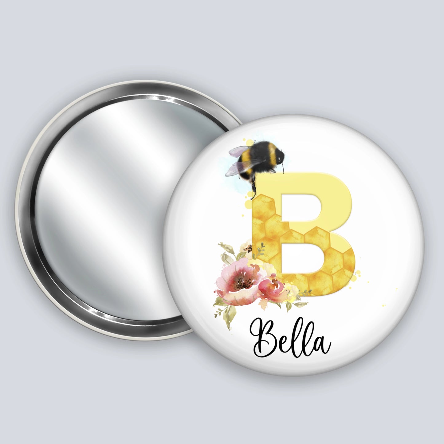 Personalised hand held badge mirror featuring the image of a bee, honeycomb alphabet letter and flowers.