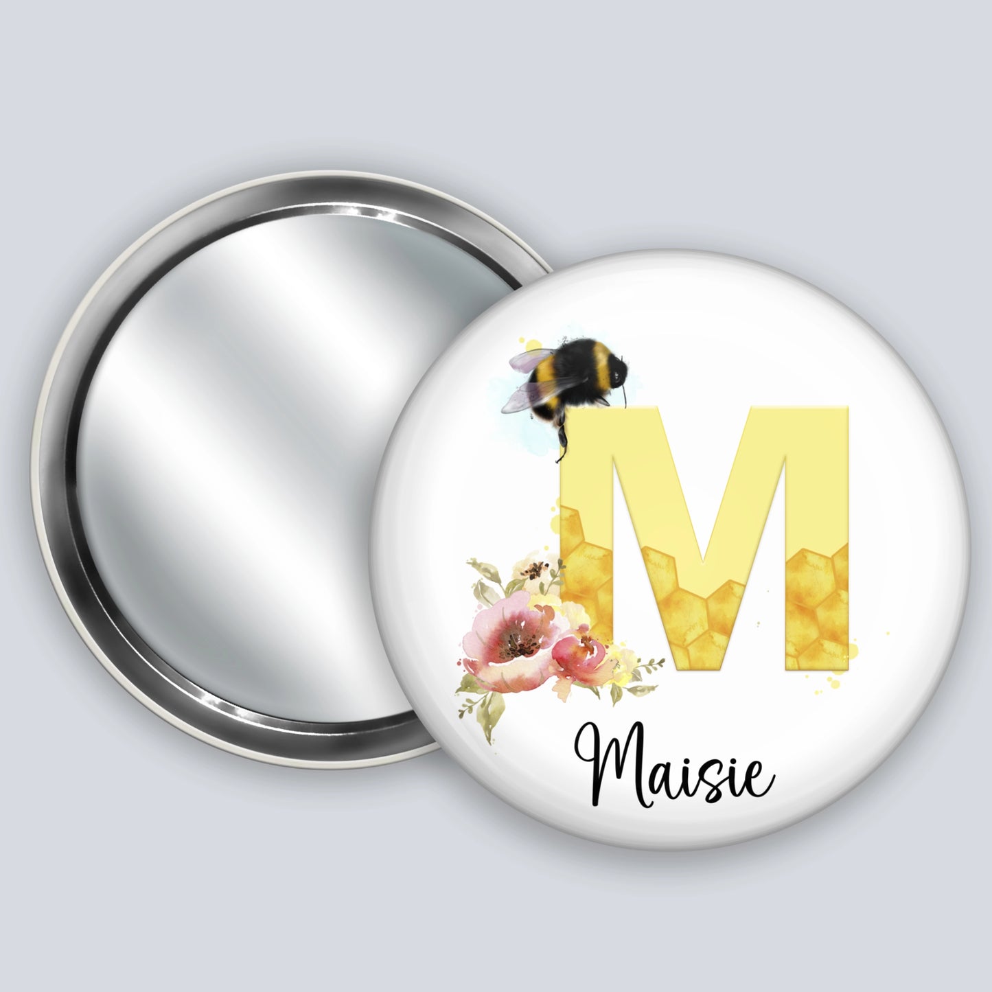 Personalised hand held badge mirror featuring the image of a bee, honeycomb alphabet letter and flowers.