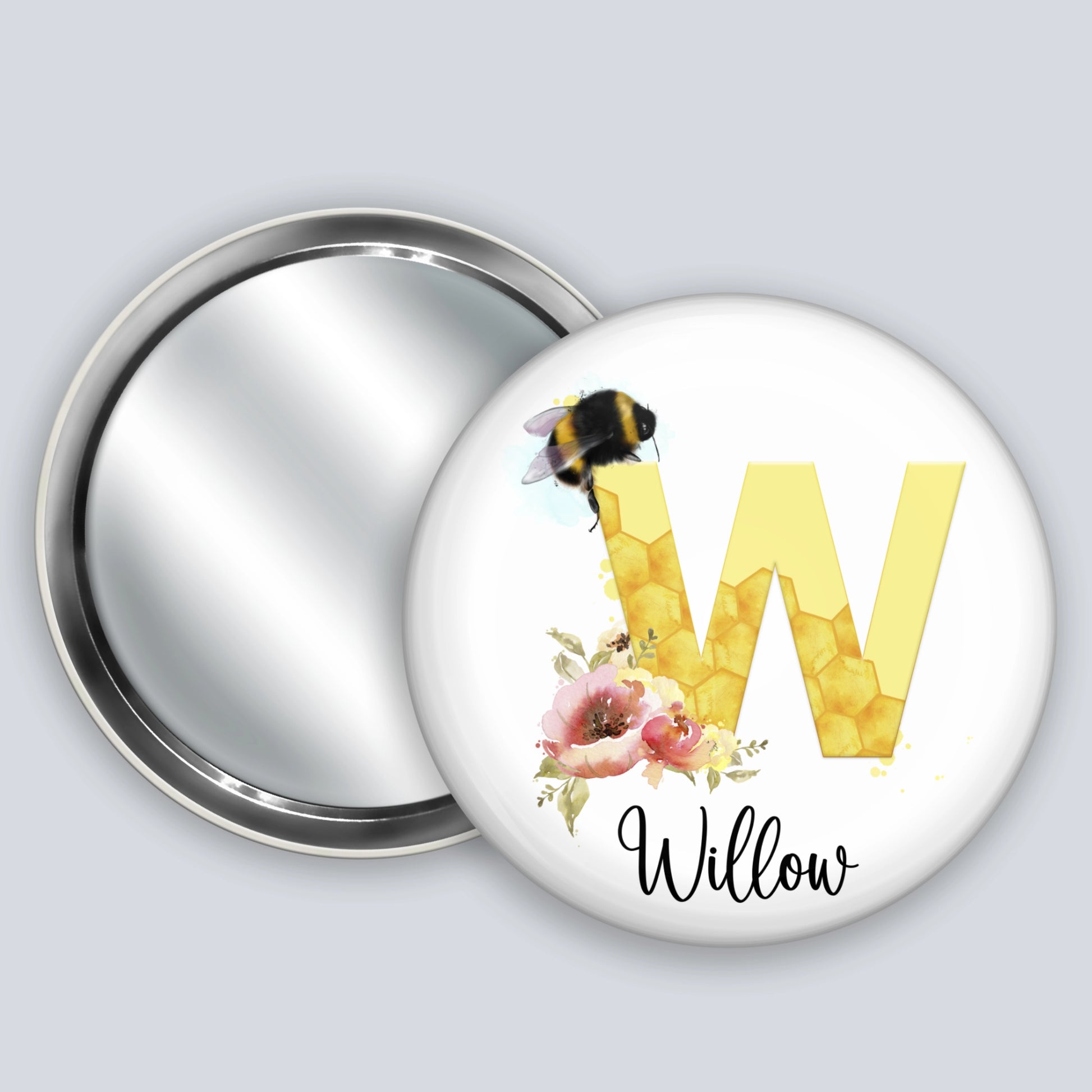 Personalised hand held badge mirror featuring the image of a bee, honeycomb alphabet letter and flowers.