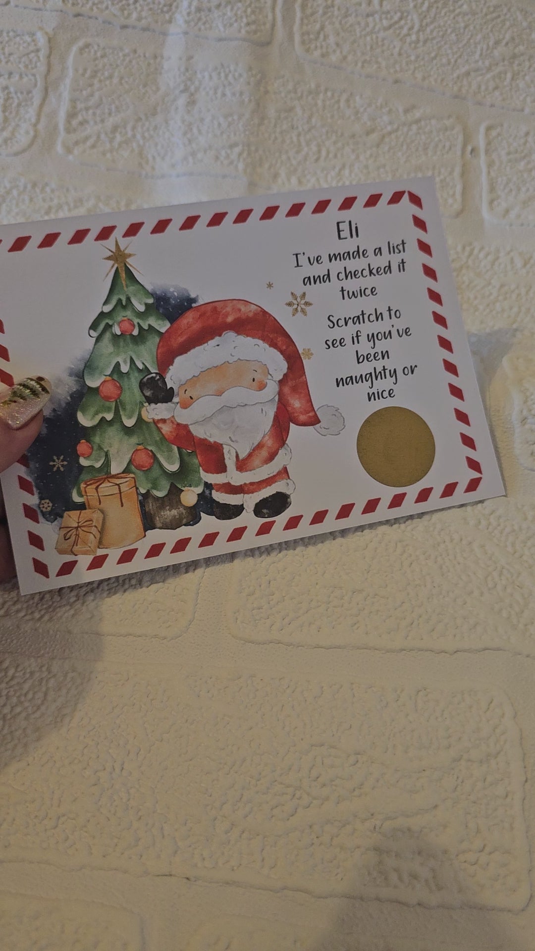 A ideo of a card with an image of Santa Claus next to a Christmas tree with the text 'I've made a list and checked it twice. Scratch to see if you've been naughty or nice' This is personalised and has a gold scratch off sticker