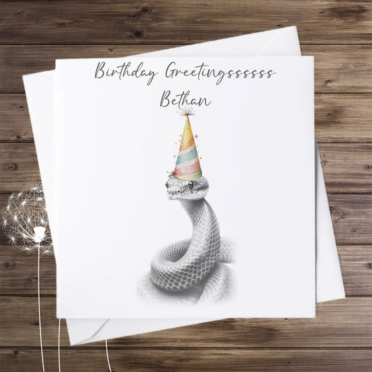 Birthday card featuring a greyscale sketch of a snake wearing a coloured  birthday hat. The card is personalised.