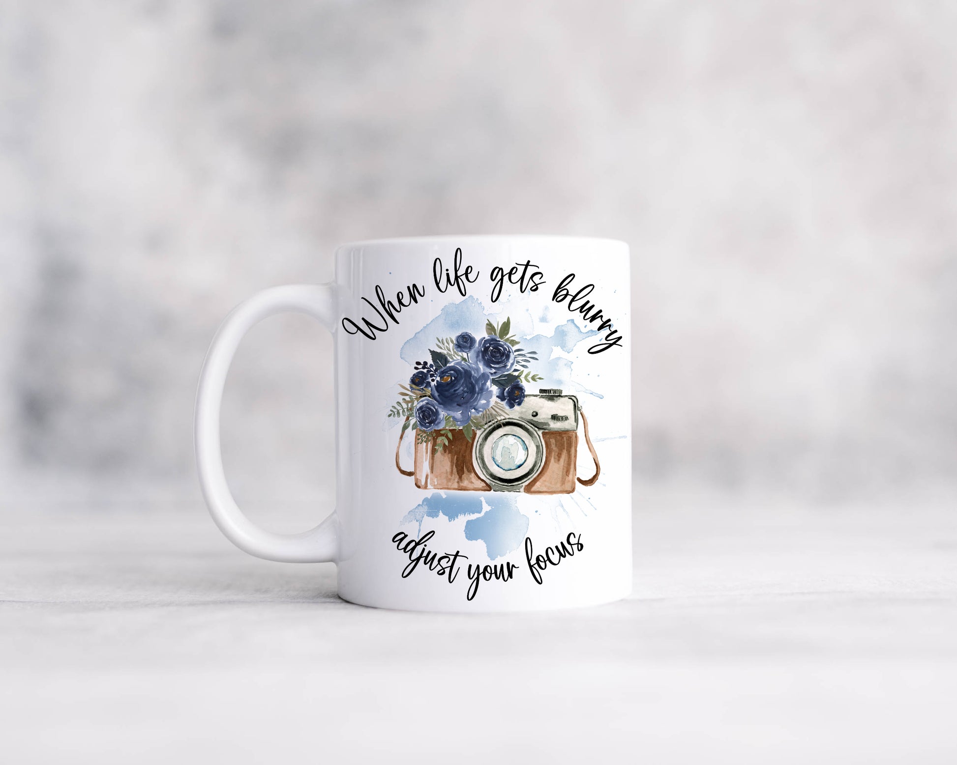 Retro camera design with blue flowers on a blue watercolour splash with the text 'When life gets blurry, adjust your focus'