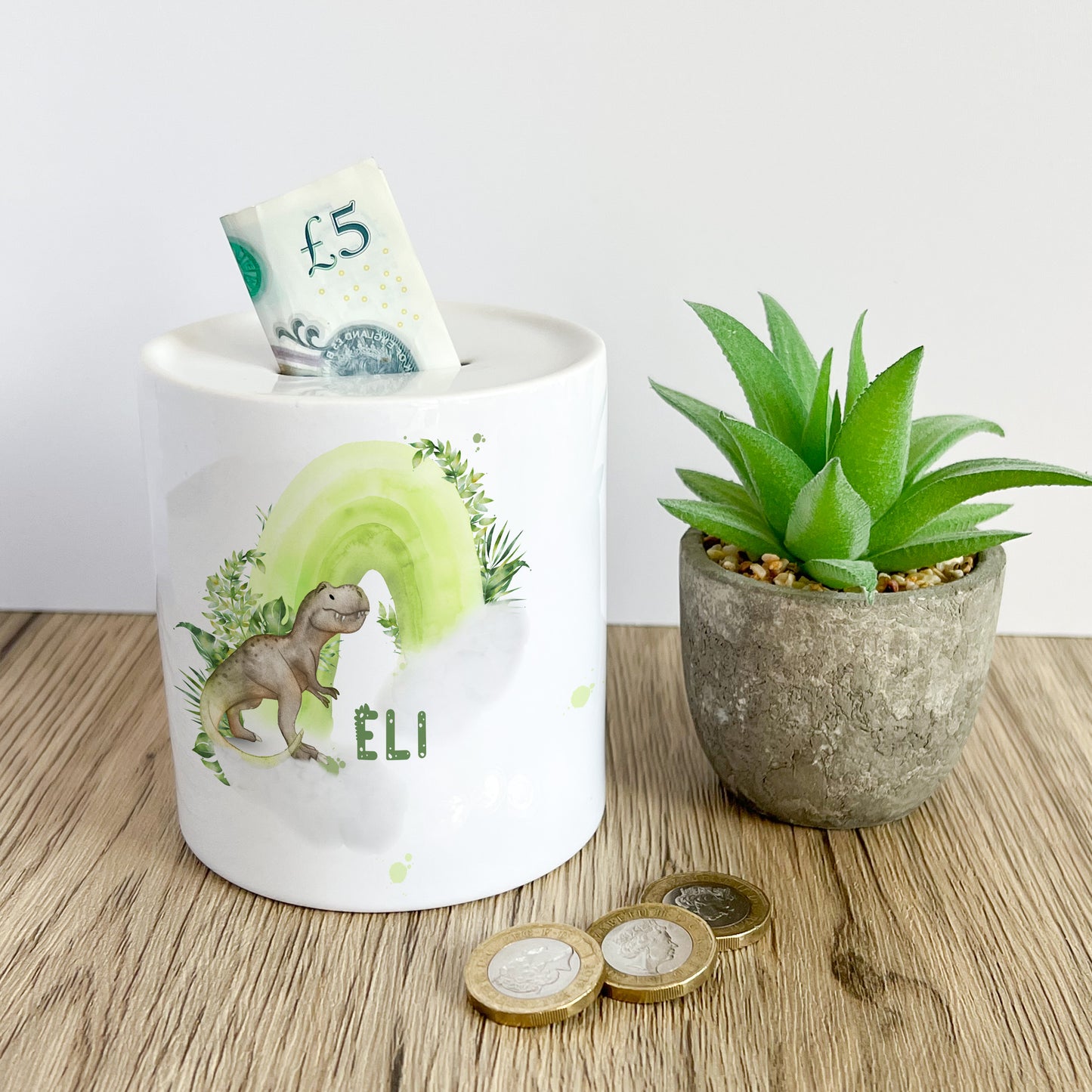 Personalised ceramic money box with a dinosaur and rainbow