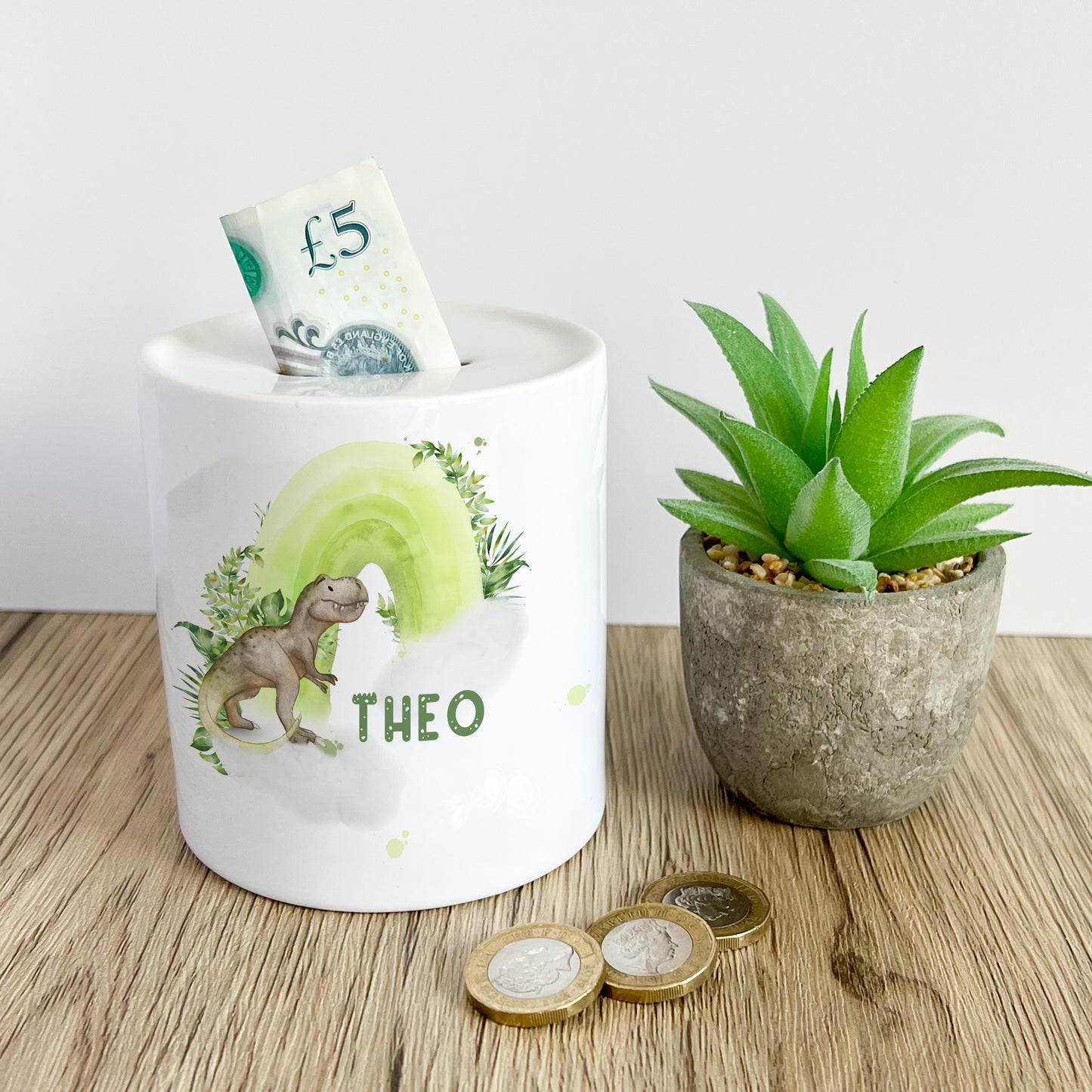 Personalised ceramic money box with a dinosaur and rainbow