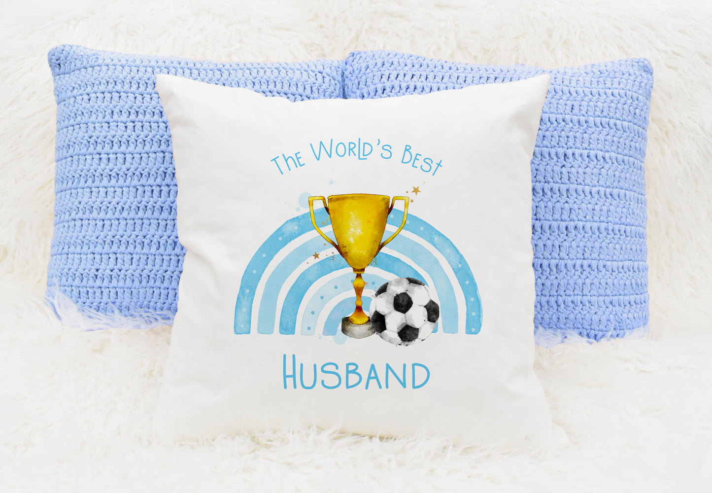 Square cushion featuring a rainbow in blue, a trophy and a football. Text reads 'The World's Best' and can be personalised