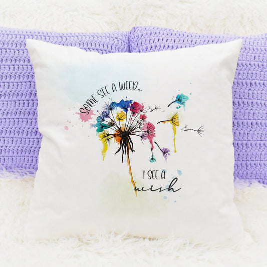 Square cushion with inner that features a bright watercolour dandelion design and text that reads 'Some see a weed, I see a wish' 
