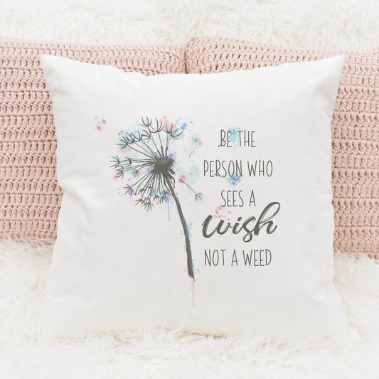 Square cushion with inner that features a pastel dandelion design and text that reads 'Be the person who sees a wish not a weed'
