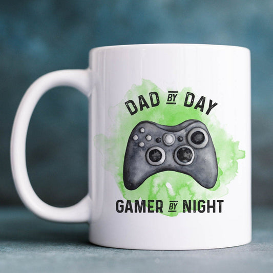 Ceramic mug with a green watercolour splash behind a gaming controller and the text 'Dad by day, gamer by night'