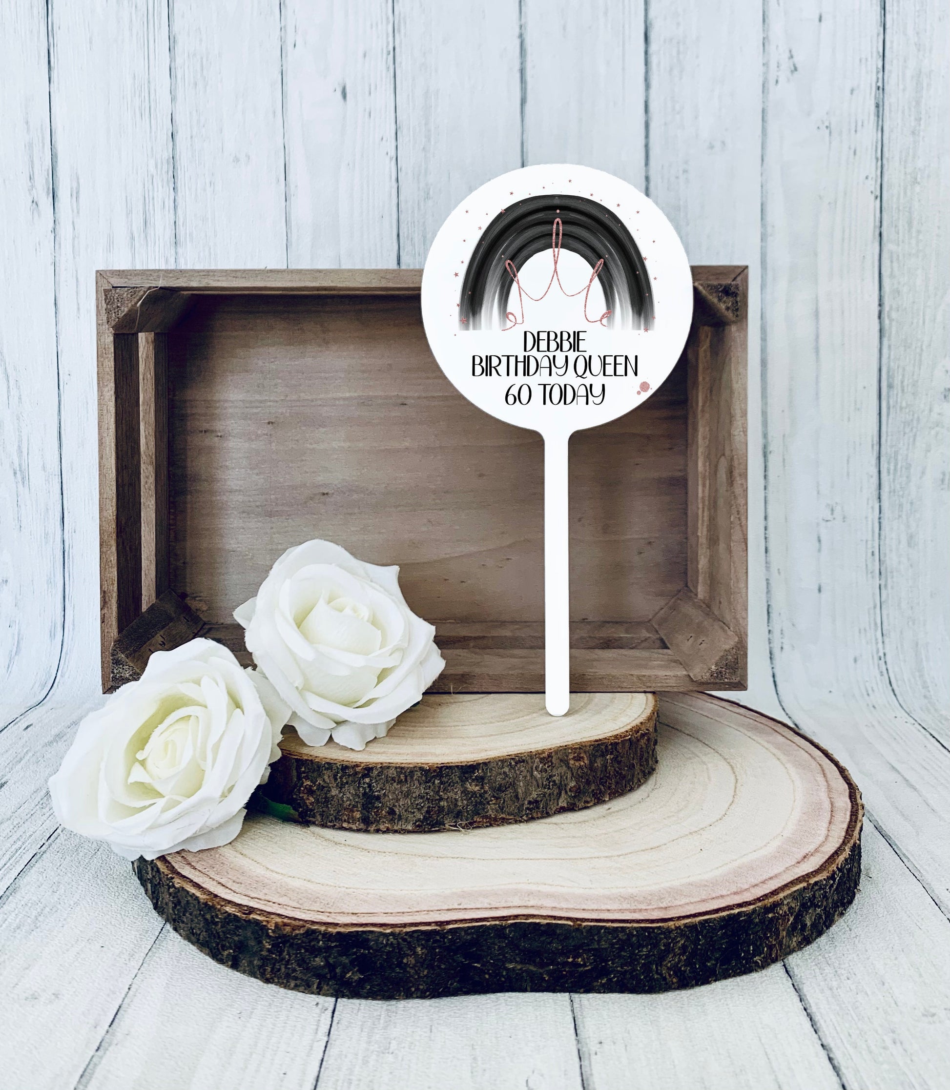 Acrylic round cake topper featuring a black rainbow and a rose gold crown with personalised birthday text