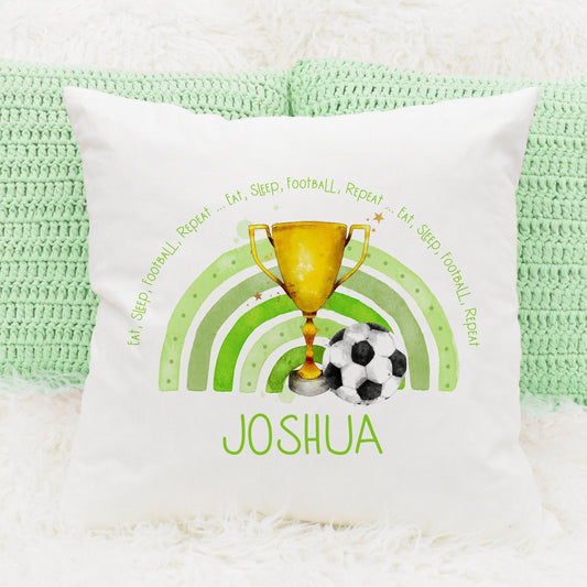 Square cushion featuring a green rainbow, a trophy and a football. The text reads 'eat, sleep, football, repeat...' Can be personalised