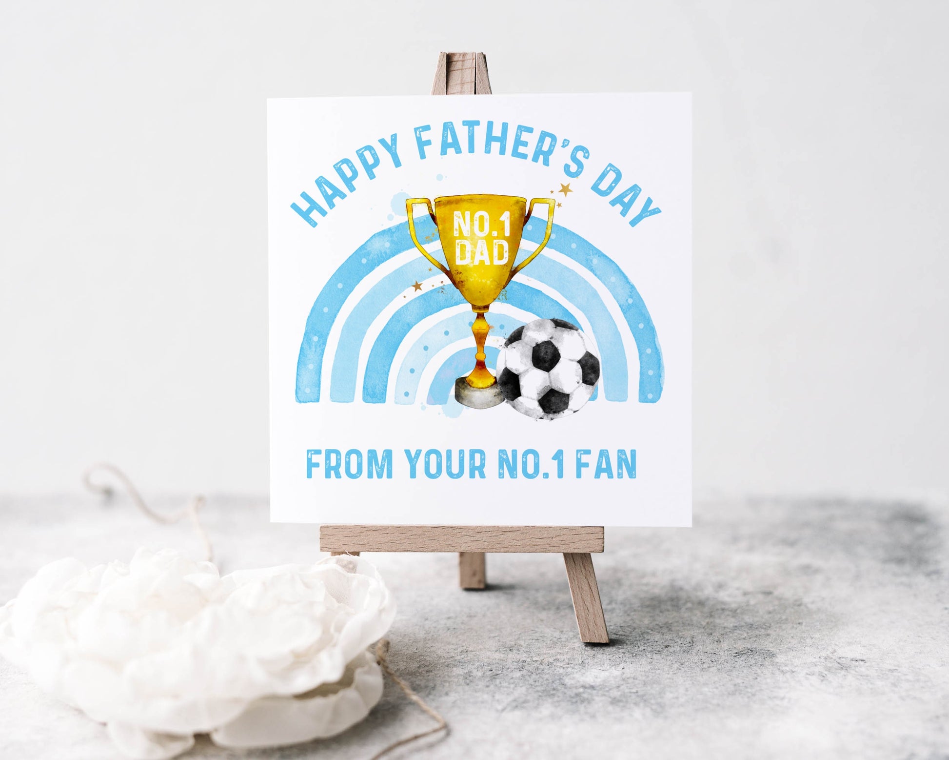 Father's day greeting card, the design features a trophy, a blue rainbow and a football, text reads 'Happy Father's Day from your no.1 fan'
