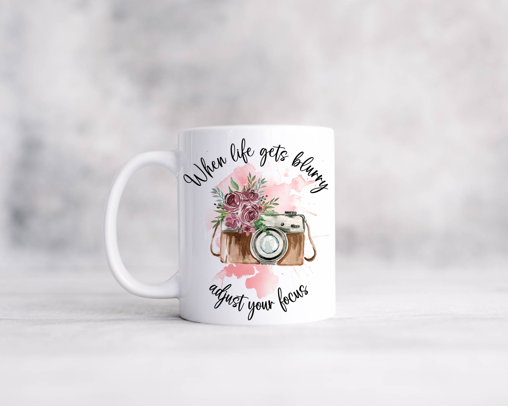 Retro camera design with pink flowers on a pink watercolour splash with the text 'When life gets blurry, adjust your focus'